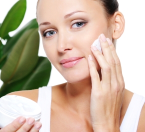 Woman holding moisturizer cream and applying it on her face